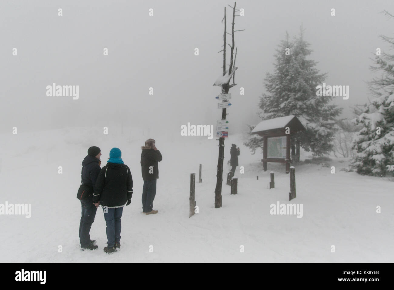 Tourists wondering in snow looking at the trail map on a foggy summit of Skrzyczne mountain in Szczyrk, southern Poland in the Silesian Voivodeship Stock Photo