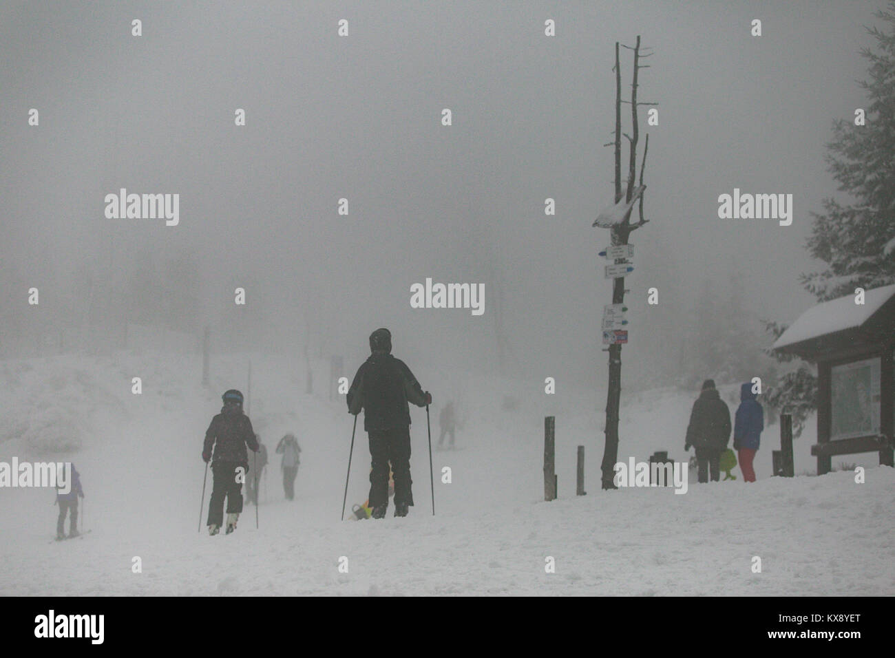 Skiers snowboarders and hikers arriving at covered in snow and mist summit of Skrzyczne mountain in Szczyrk heading for the slopes and hiking trails Stock Photo
