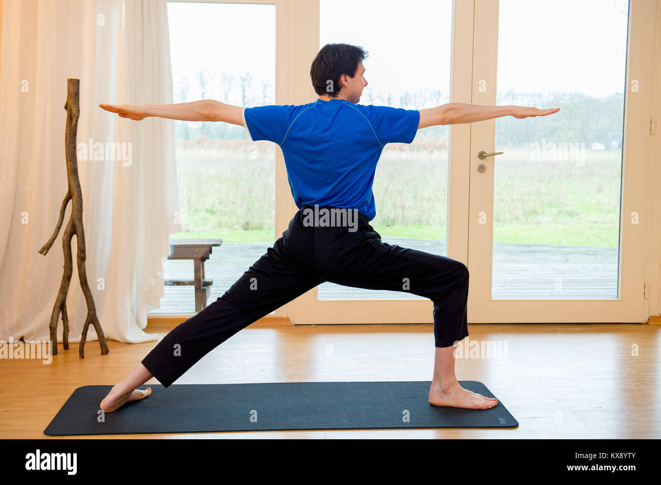 Man practicing yoga indoors in a retreat space doing Warrior 3 pose -  Viradhadrasana III Stock Photo - Alamy