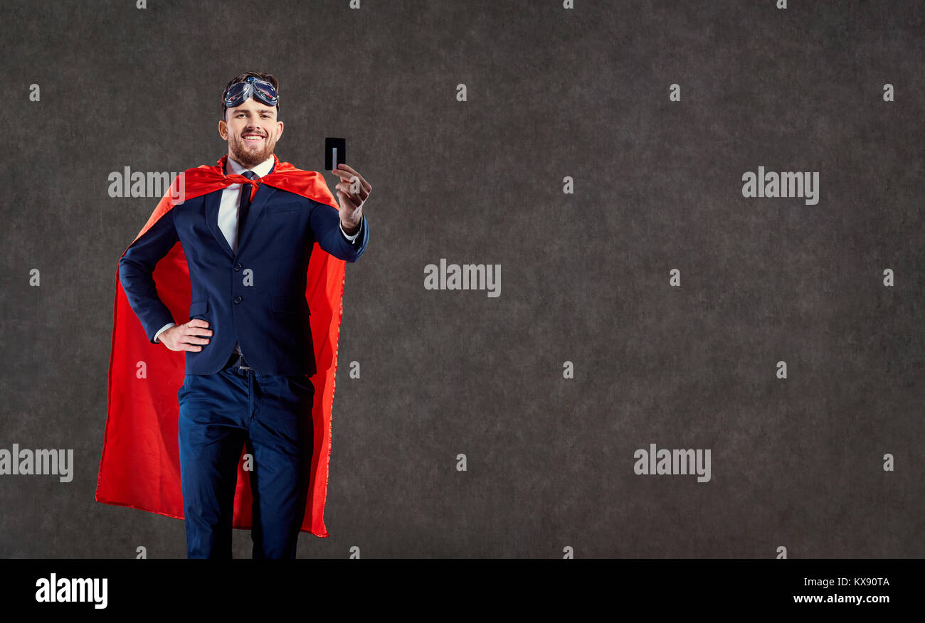 A funny man in a superhero costume keeps a credit card. Stock Photo