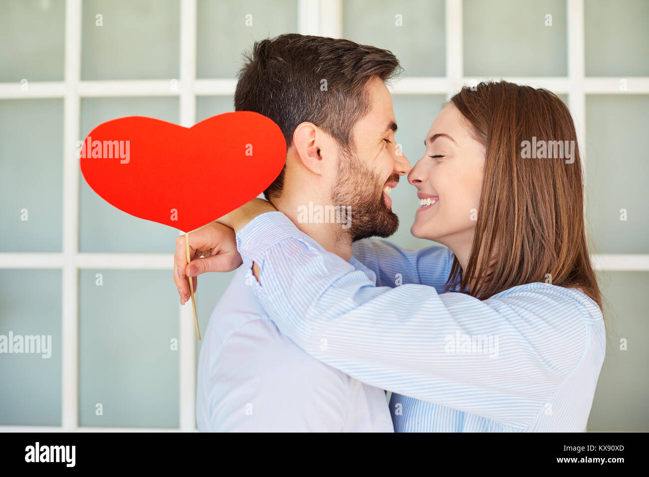 A loving couple with a red heart laugh. Stock Photo
