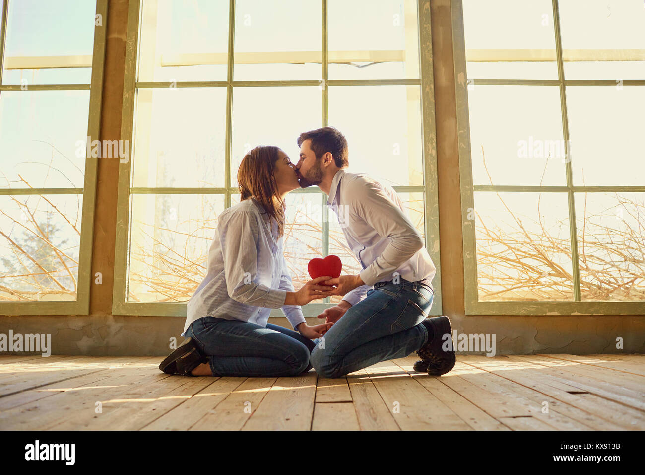 A loving couple with a red heart kissing Stock Photo - Alamy
