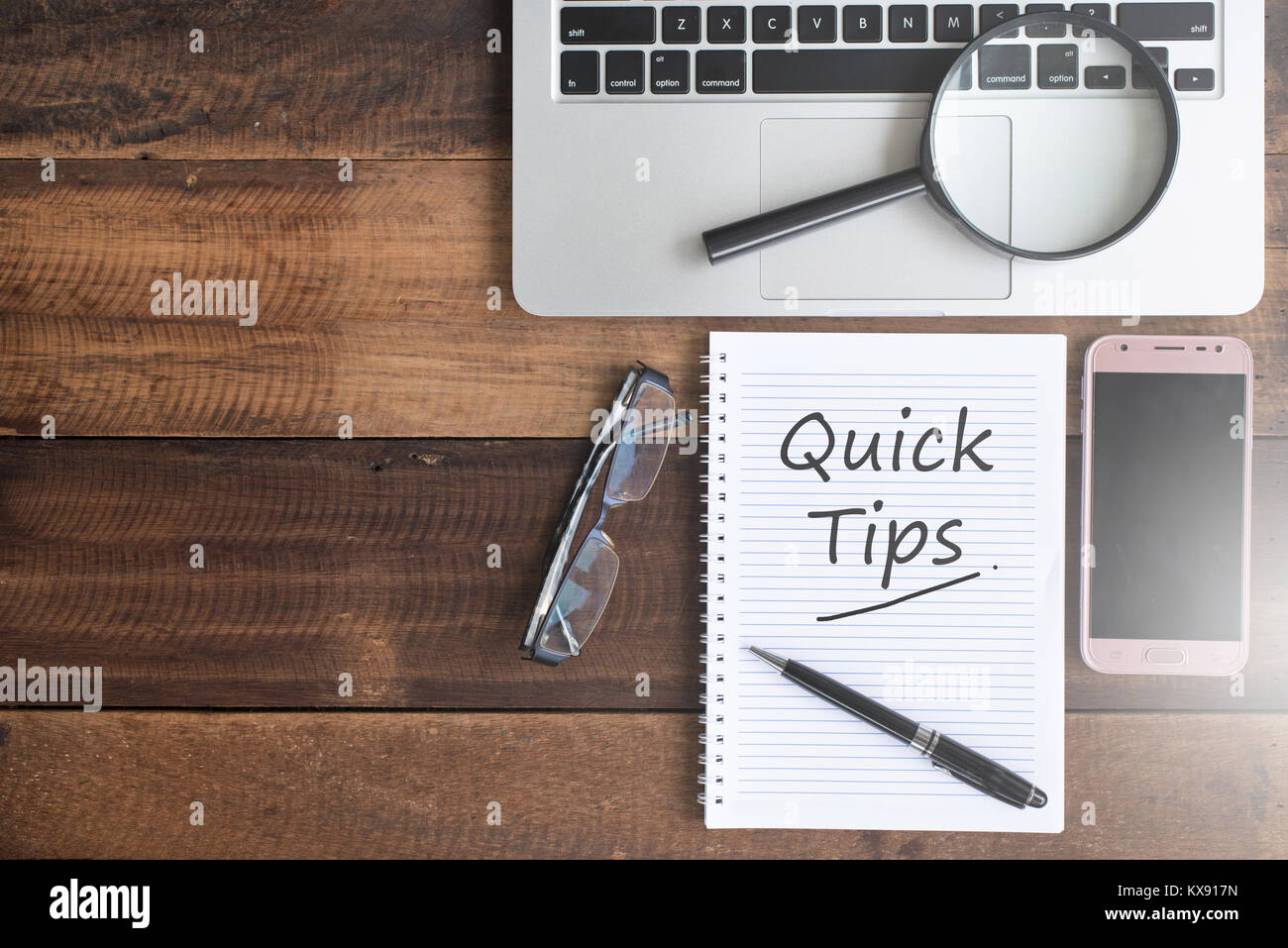 Notebook, smartphone, magnifying glass, spectacles and QUICK TIPS word. quick tips flat lay concept Stock Photo