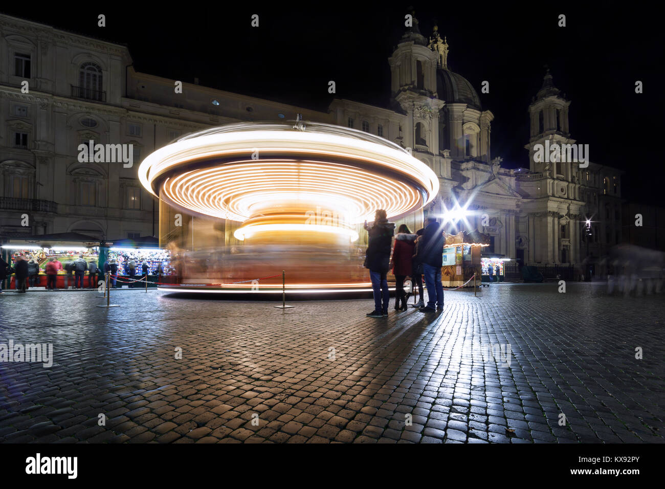 Rome, Italy - December 23, 2017: The rotating carousel with horses, in Piazza Navona. In the background the Church of Sant'Agnese in Agone. Night phot Stock Photo