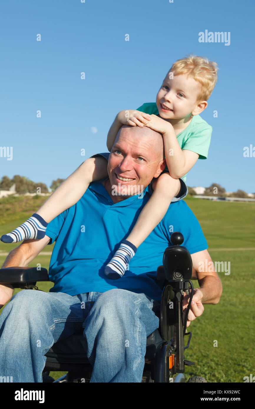 Disabled father giving little son piggyback ride Stock Photo