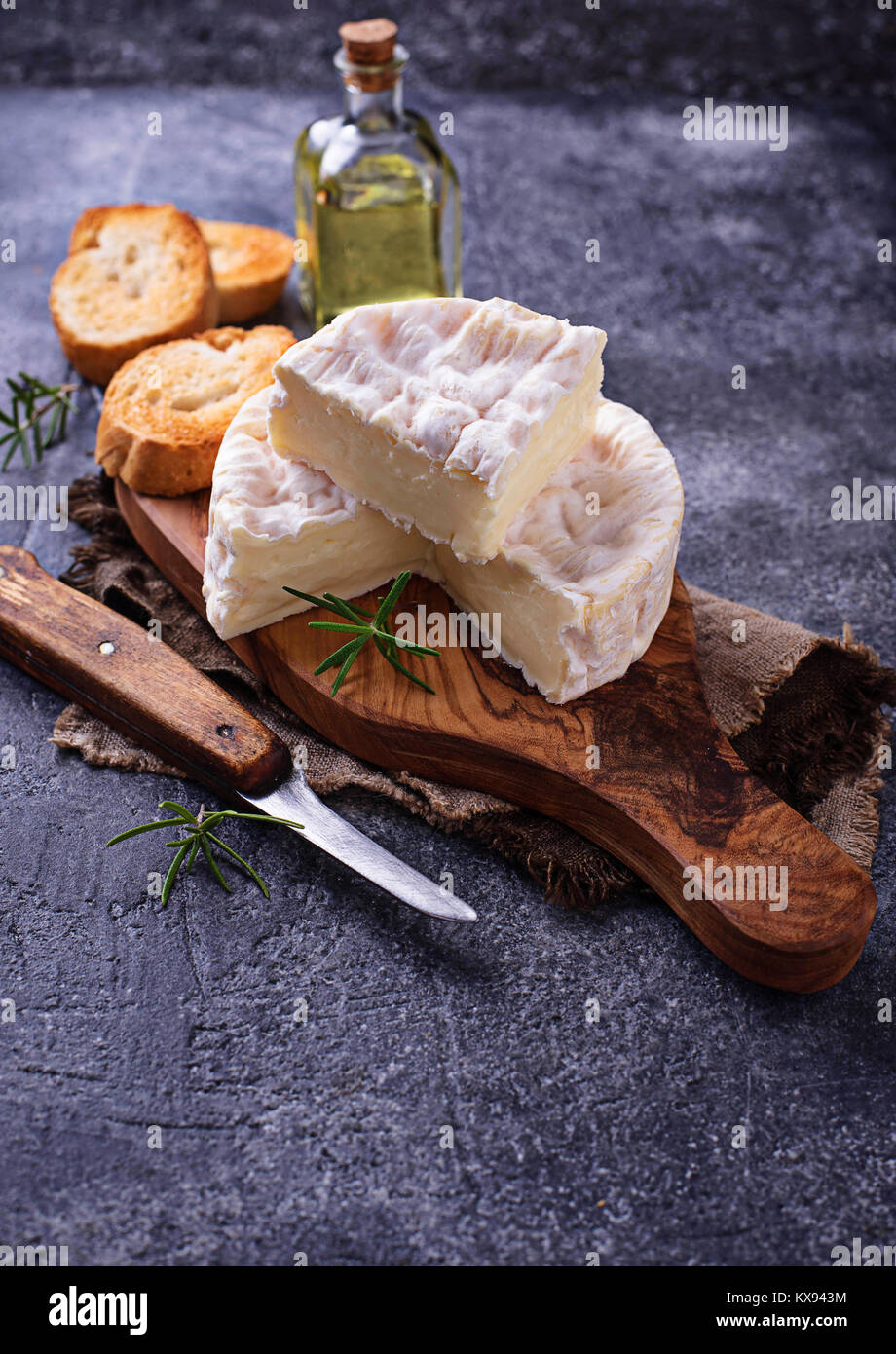 Camembert cheese with rosemary on wooden board Stock Photo