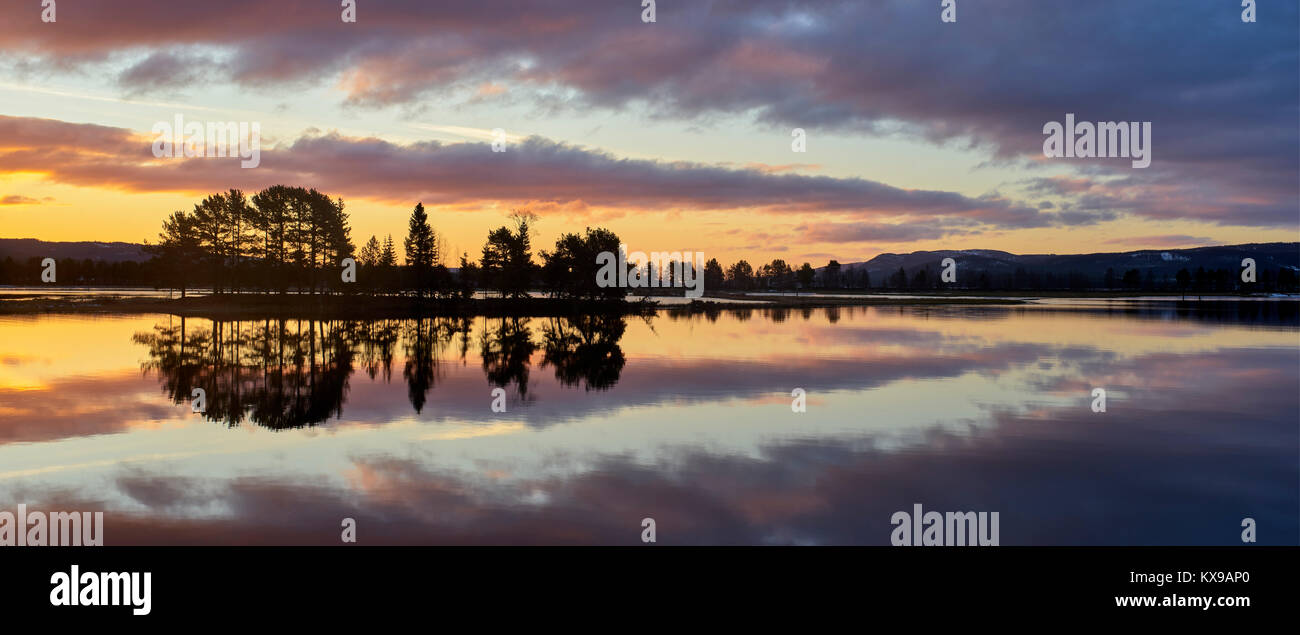 Panoramic sunrise over Osensjoen from Sandvik, Hedmark, Norway.  Mirror image reflection Stock Photo