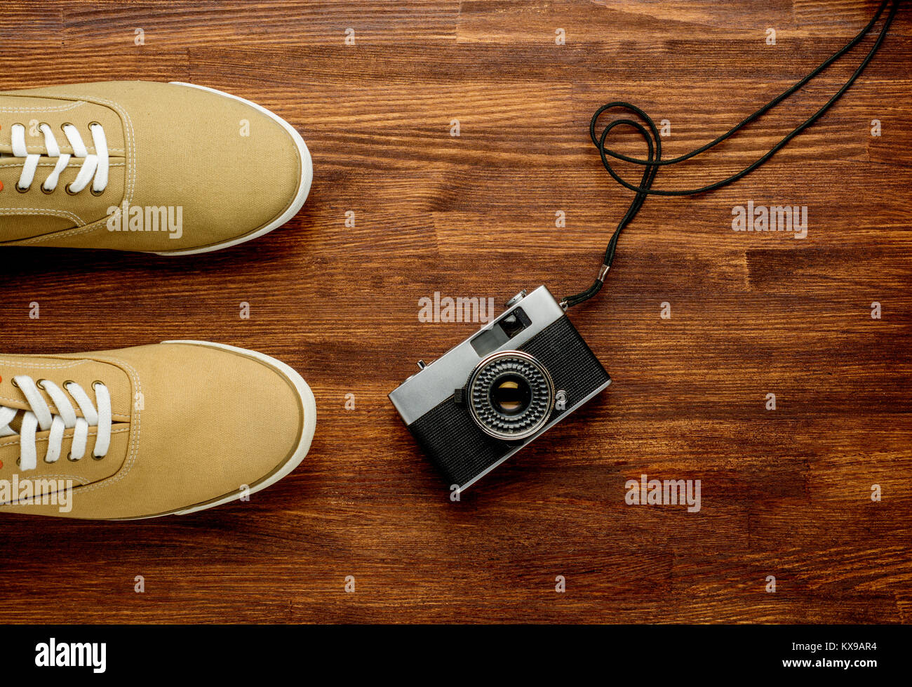 Vintage camera with sneakers on wooden background. Travel background. Horizontal Stock Photo