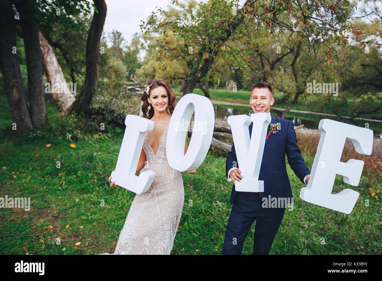 Happy Wedding Couple Holding Big White Love Letters And Kissing