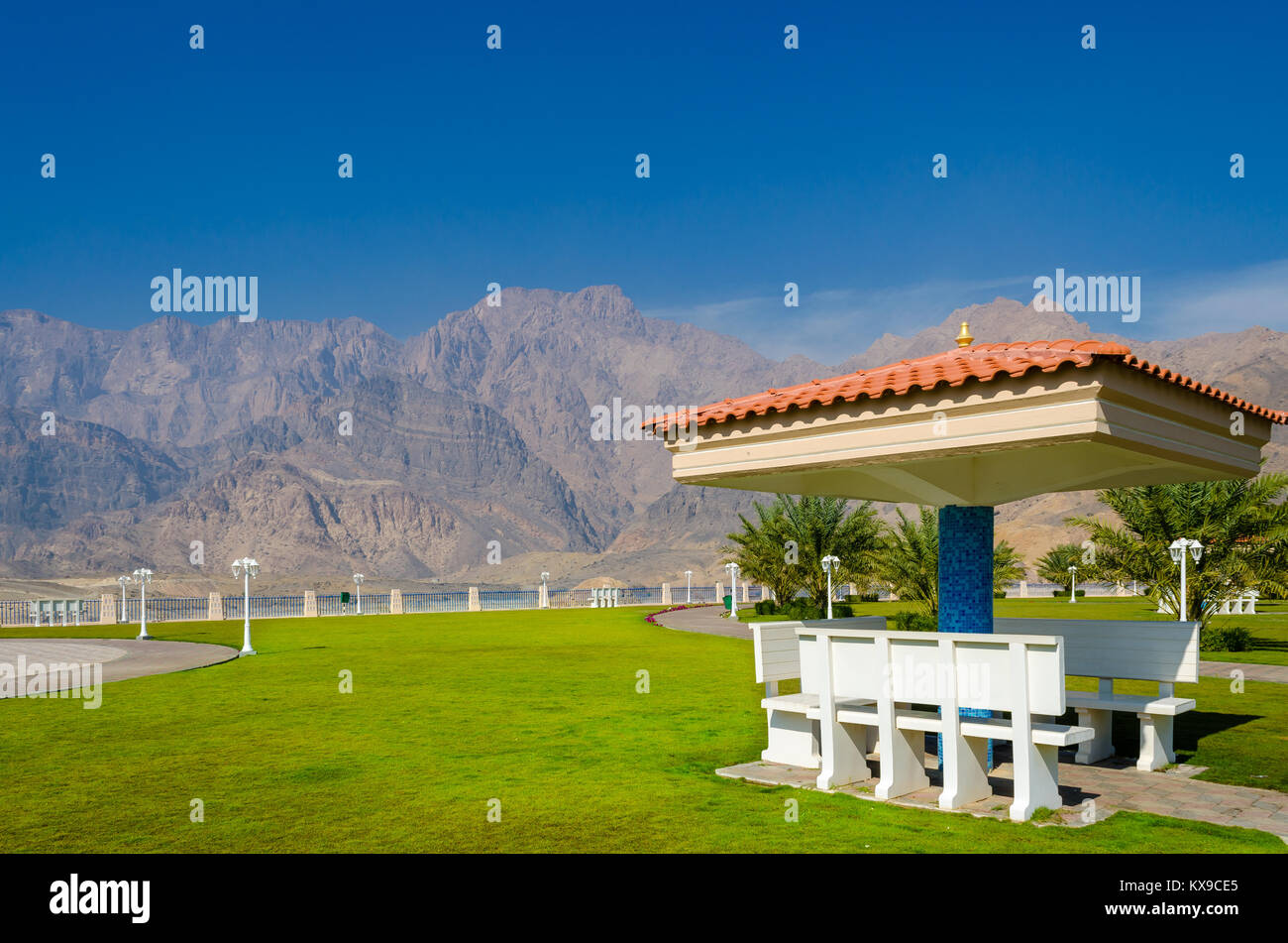 Covered benches for an ideal picnic spot with green lawn with mountains and a clear blue sky in the background. Stock Photo
