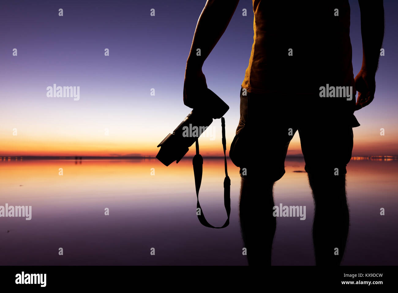 Male photographer taking picture with dslr camera on the beach at sunset time Stock Photo