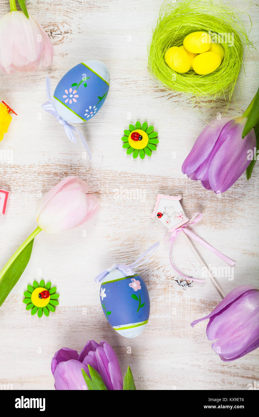 Bouquet purple tulips and Easter eggs on a light wooden table, top view ...
