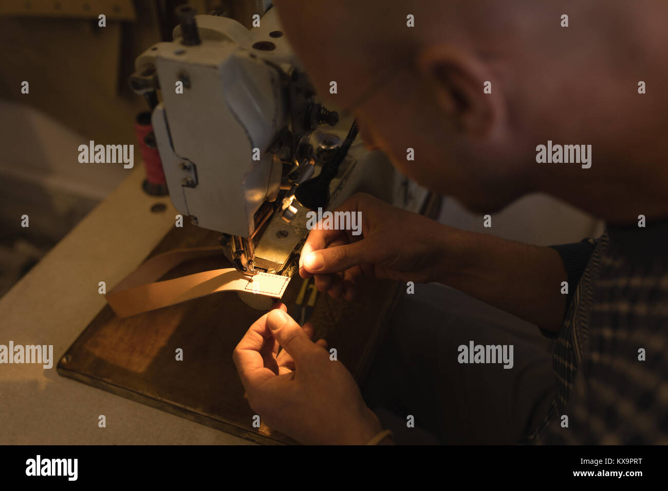 Worker sewing leather scrap in workshop Stock Photo