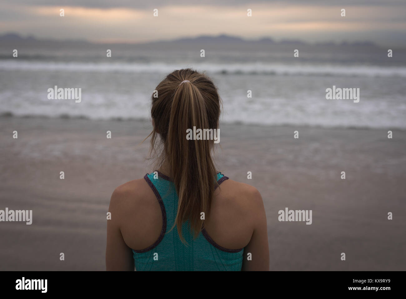 Woman in sports wear with ponytail standing at beachfront Stock Photo