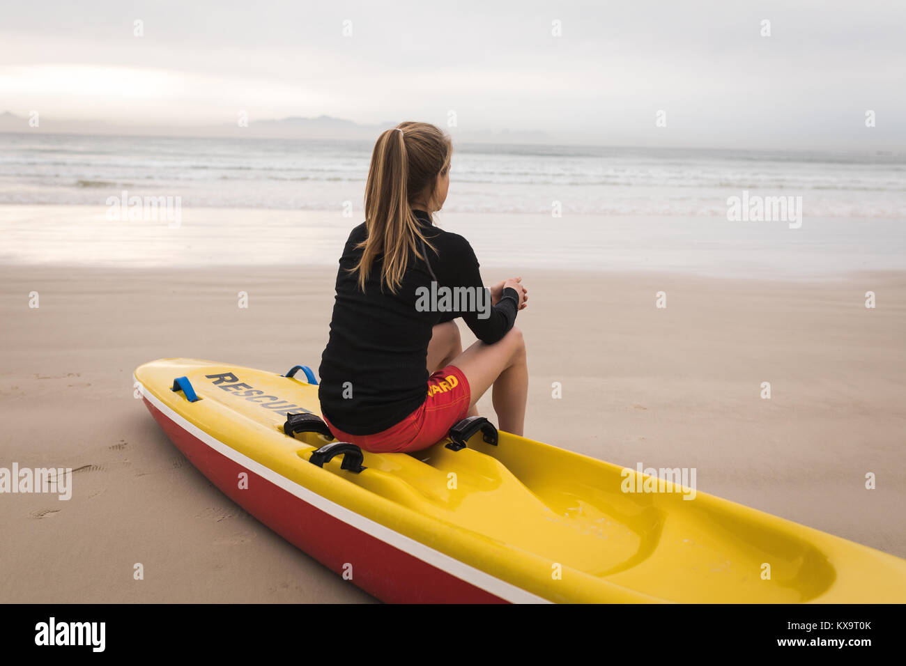 Female lifeguard sitting on rescue boat at beach Stock Photo