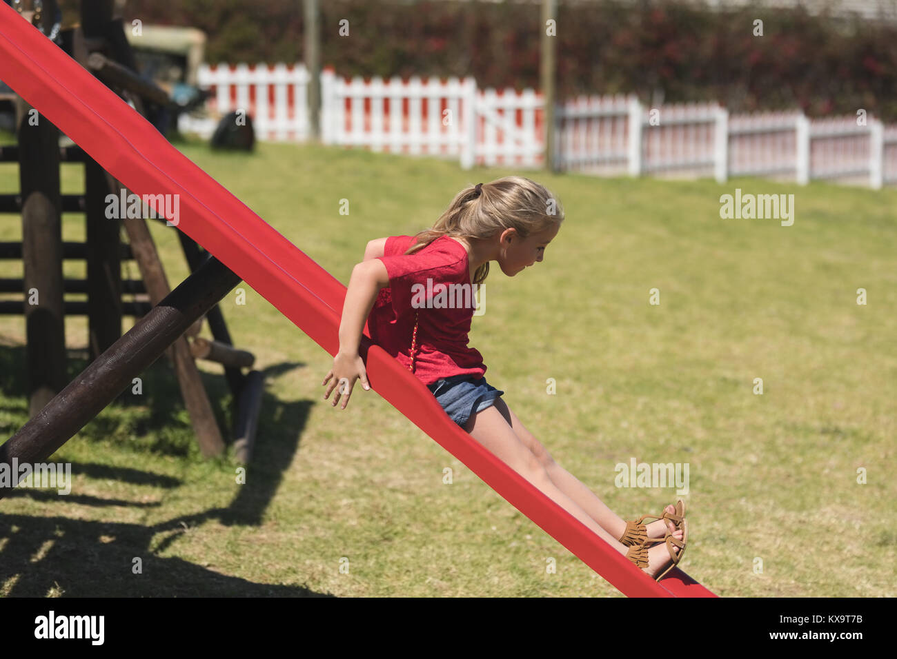Girl sliding on slide in playground Stock Photo