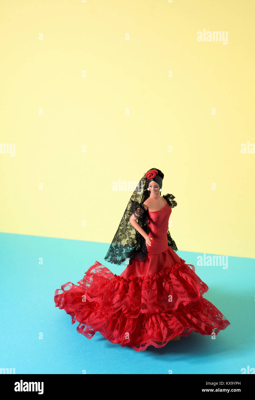 a typical spanish doll dressed as a flamenco dancer, with the characteristic traje de flamenca, the typical dot-patterned dress, in a yellow and blue  Stock Photo