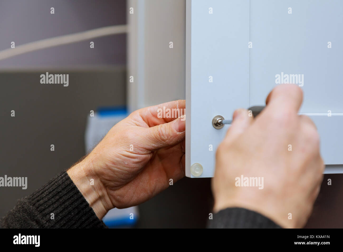 Hand on handle installation of door handles on opening door in kitchen with a