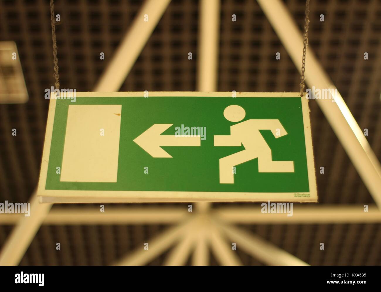 Green and white Emergency exit sign hanging from the ceiling Stock