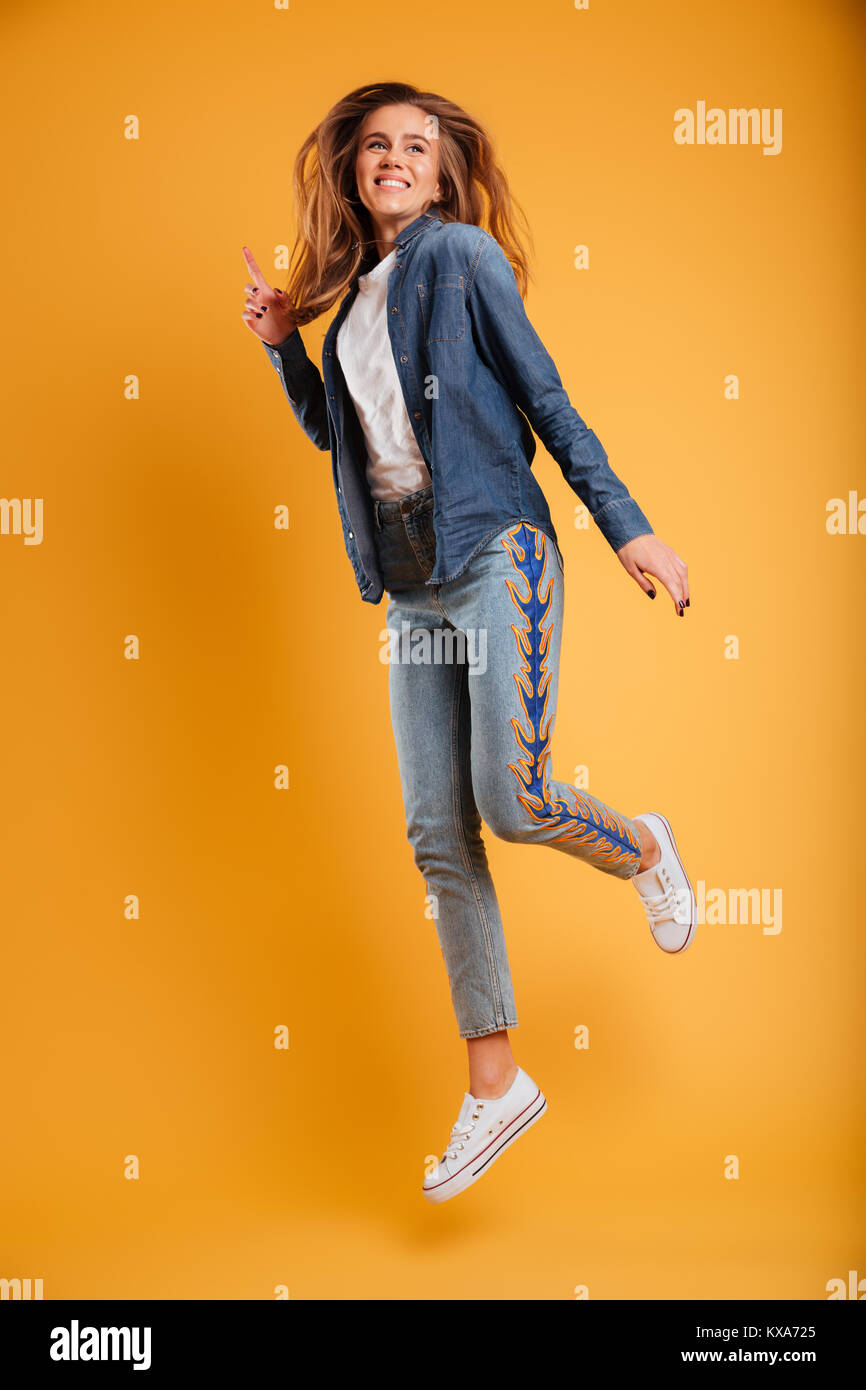 Full length portrait of a happy cheerful girl jumping and looking away ...