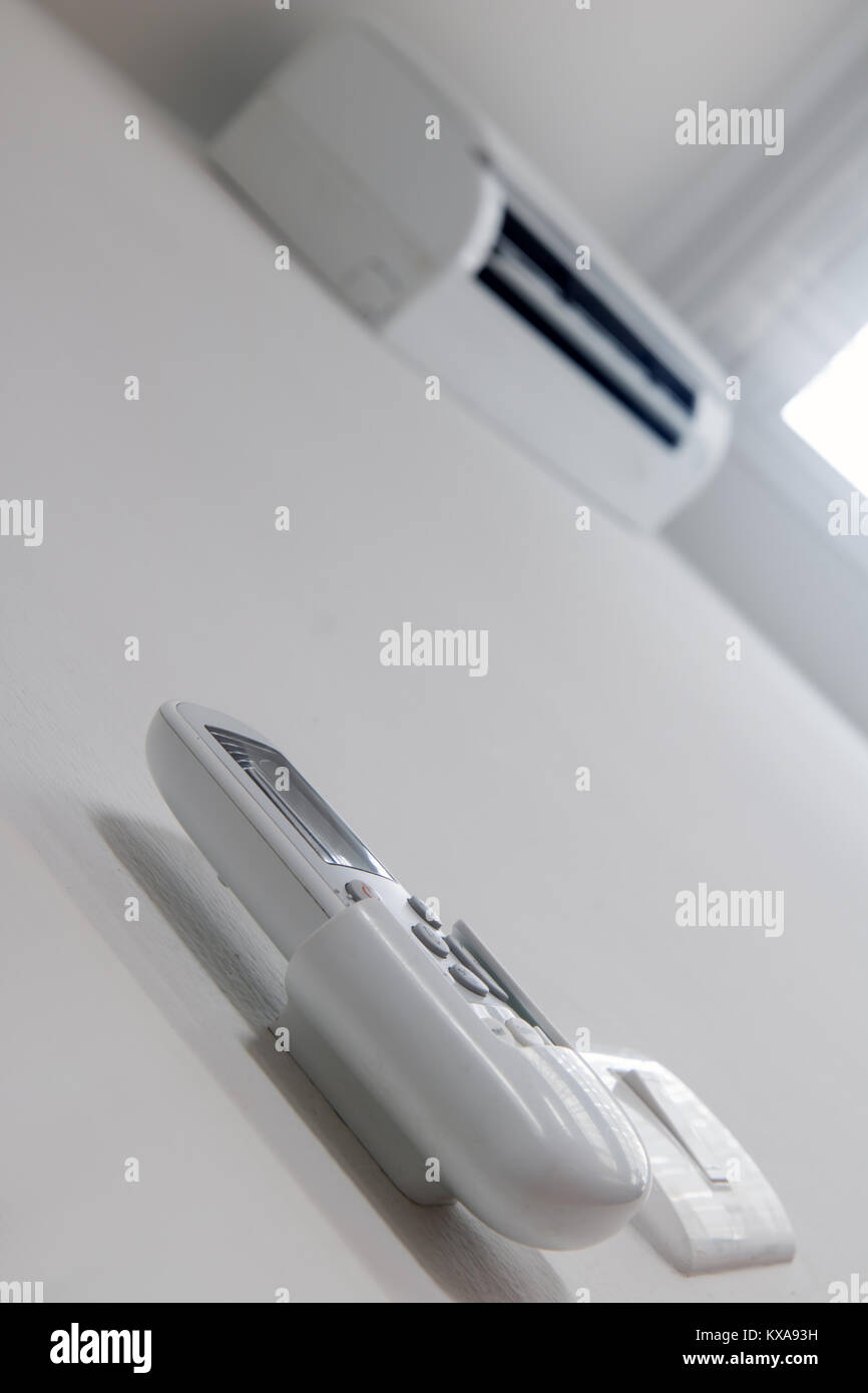 Remote control close up with air conditioner hang on white wall. Air conditioner inside the room