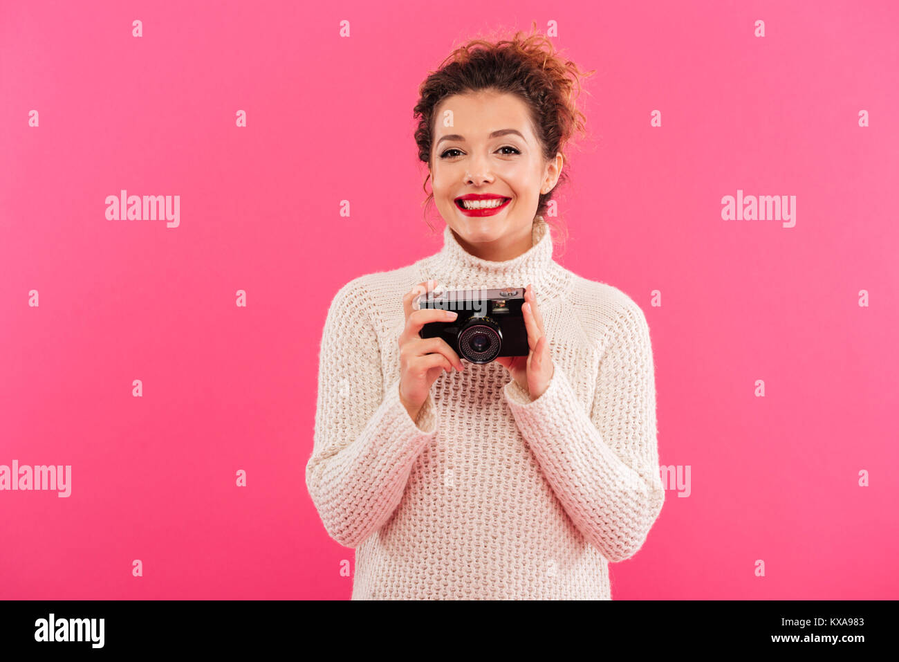 Portrait of a pretty smiling girl holding photo camera and looking at ...