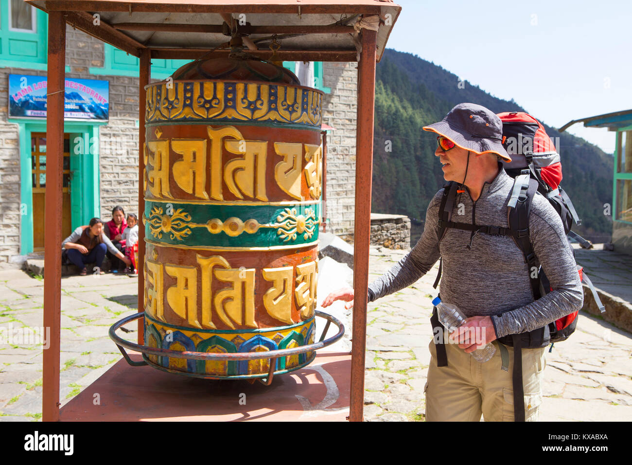 A hiker is turning a Buddhist prayer wheel along the way to Everest Base Camp. Stock Photo