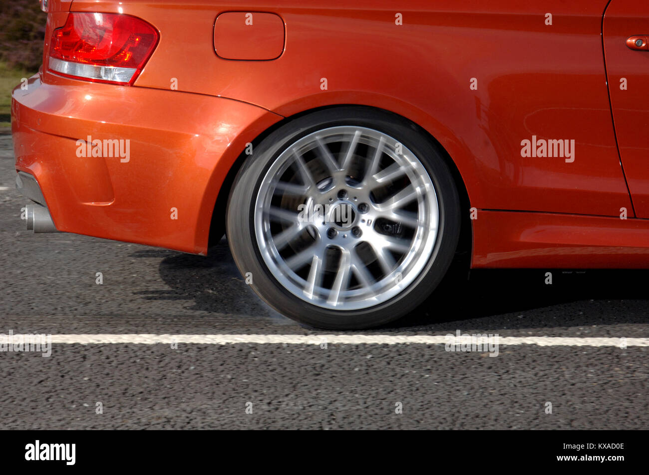 wheel spin and tyre smoke from a 2011 BMW 1M rear wheel drive German sports car Stock Photo