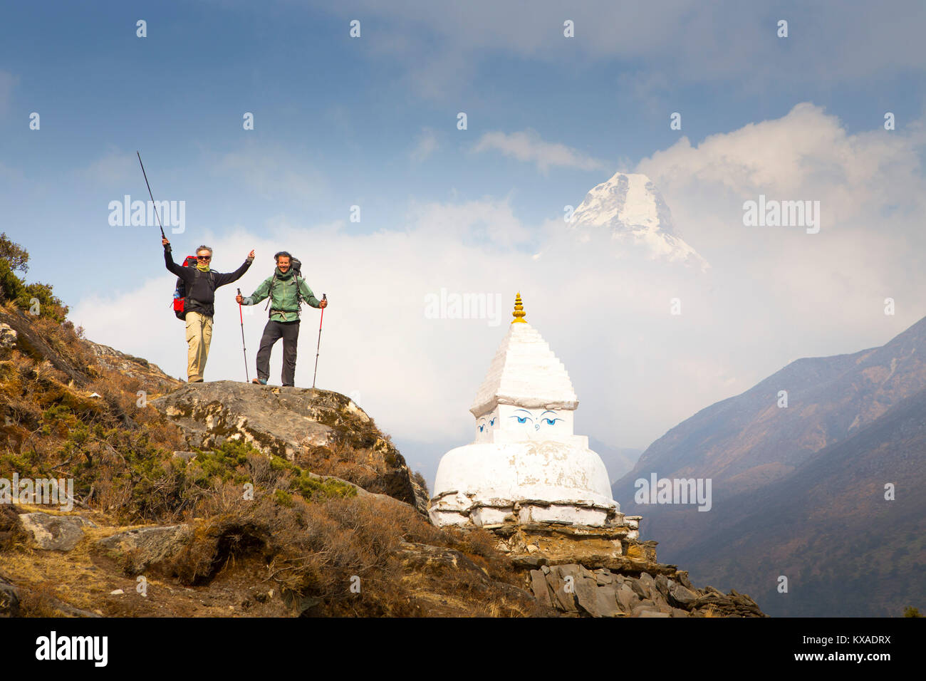 Two happy hikers near a Buddhist Stupa and with Ama Dablam mountain in the background. Stock Photo