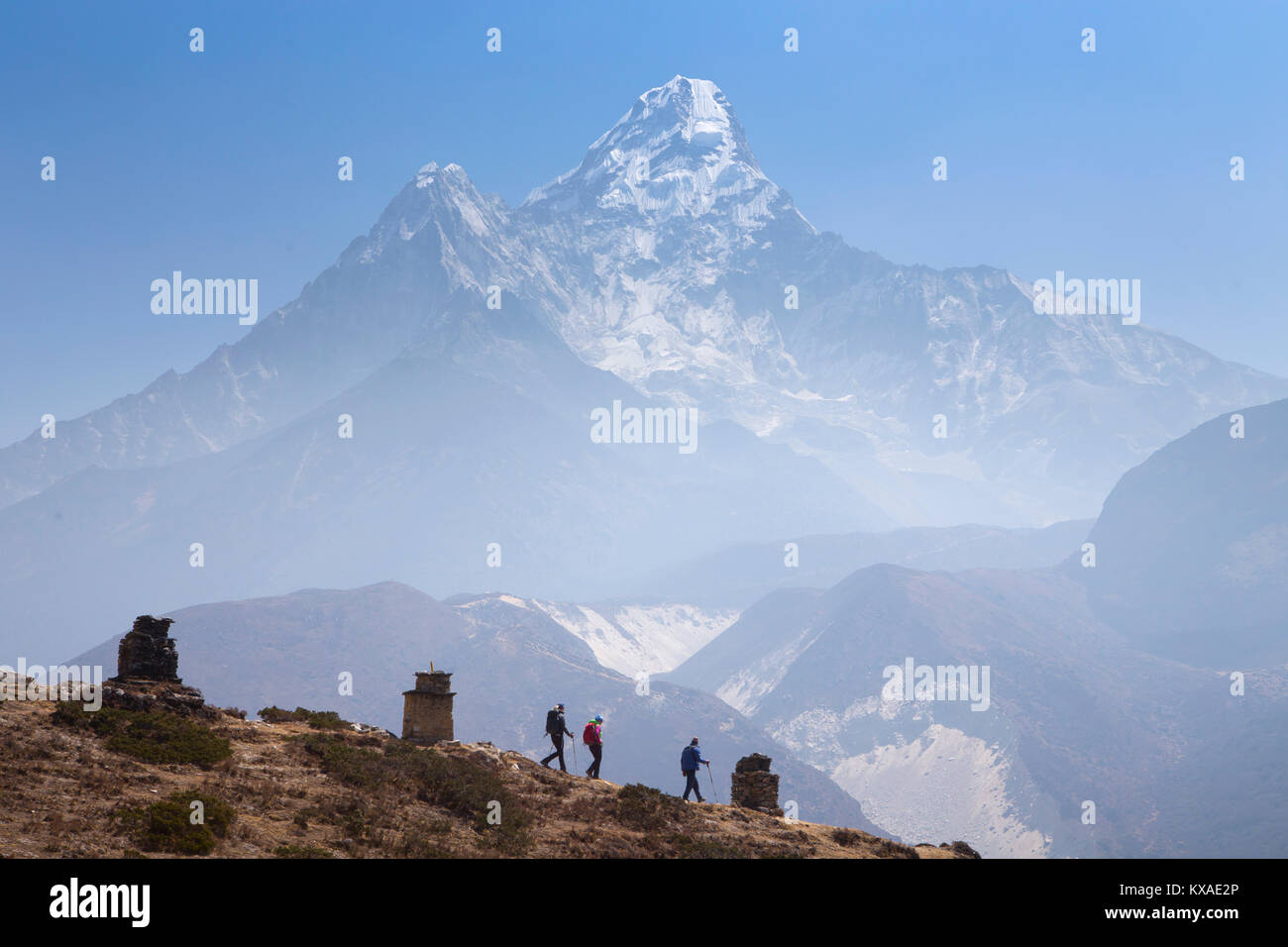 Three hikers descending from Pangboche monastery to continue their hike to Everest Base Camp, in the background Ama Dablam mountain. Stock Photo