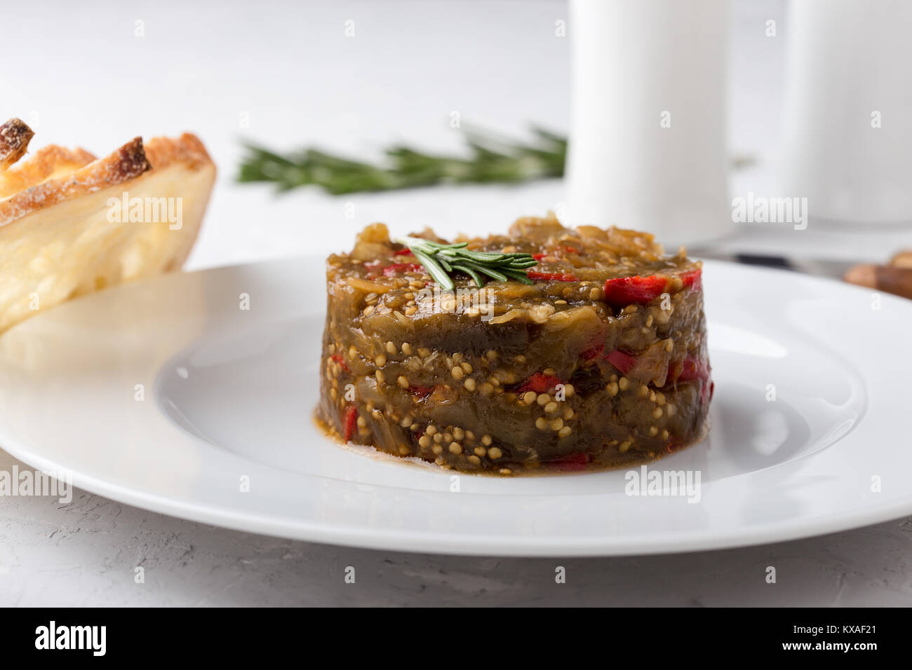 Appetizer of eggplant and red bell pepper, vegetable dip served with toasted bread on white plate Stock Photo