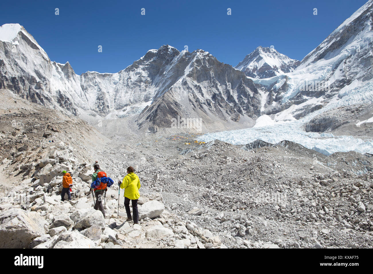 Three hikers are arriving in Everest Base Camp after a trekking through the Nepalese Khumbu valley. Stock Photo