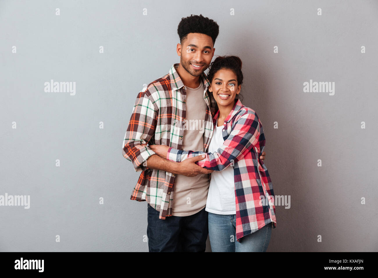 Portrait of a happy young african couple hugging while standing ...