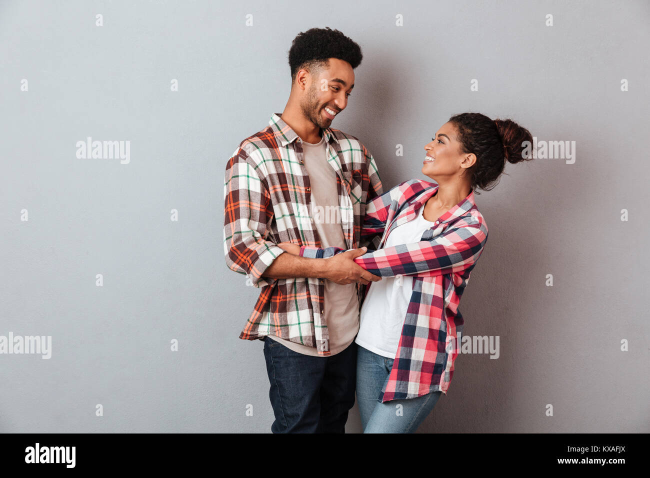 Portrait of a smiling young african couple hugging while standing ...