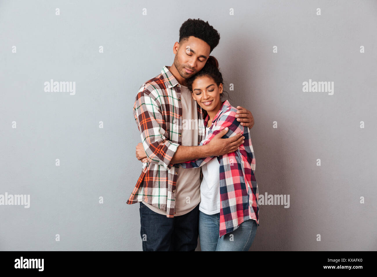 Portrait of a loving young african couple hugging while standing ...