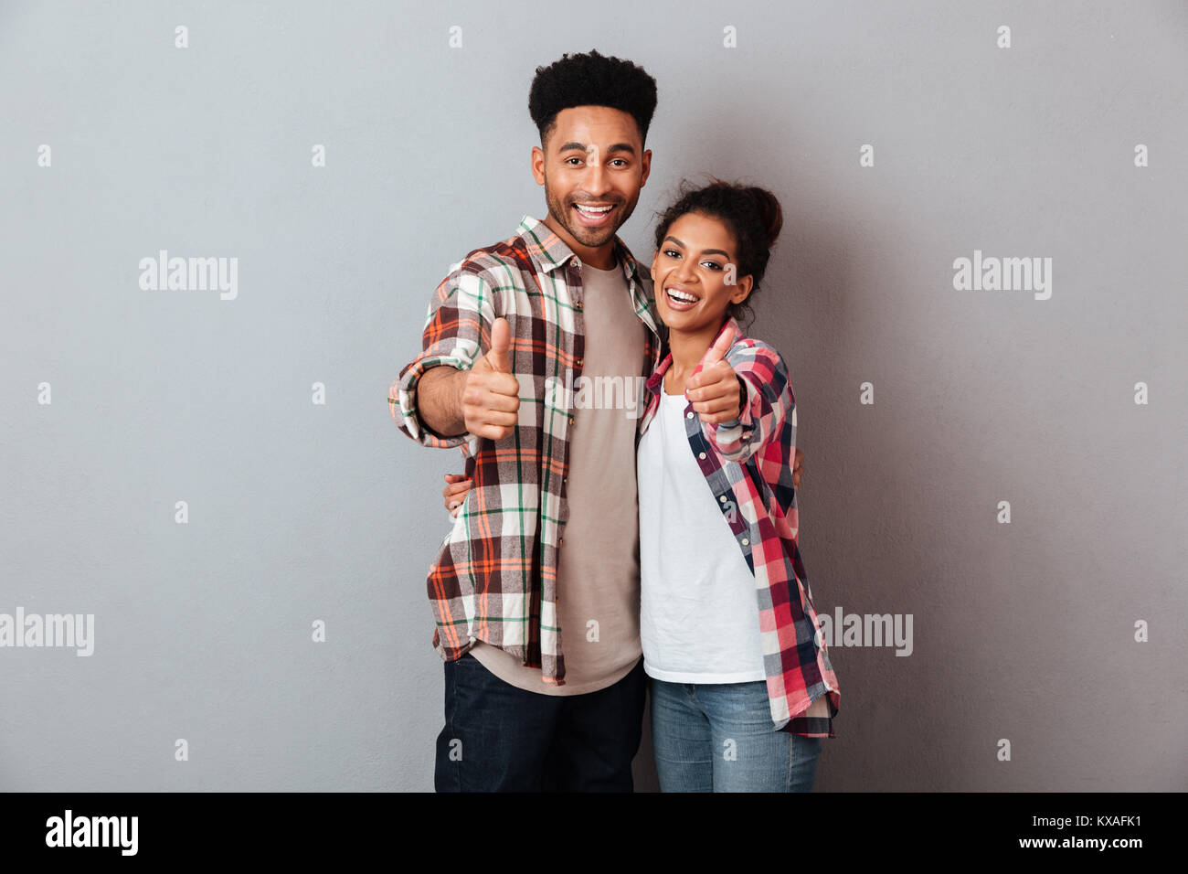 Portrait of a smiling young african couple hugging while standing ...
