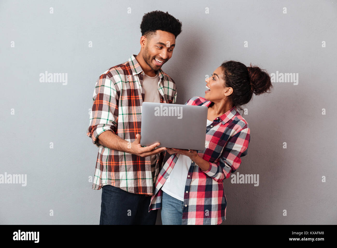 Portrait of a cheerful young african couple holding laptop computer ...