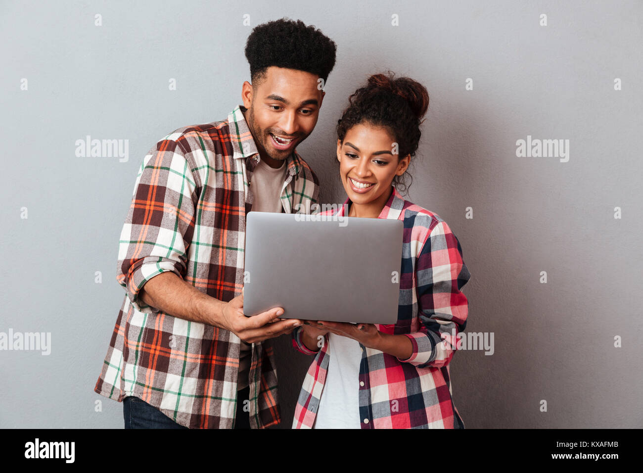 Portrait of a happy young african couple using laptop computer while ...