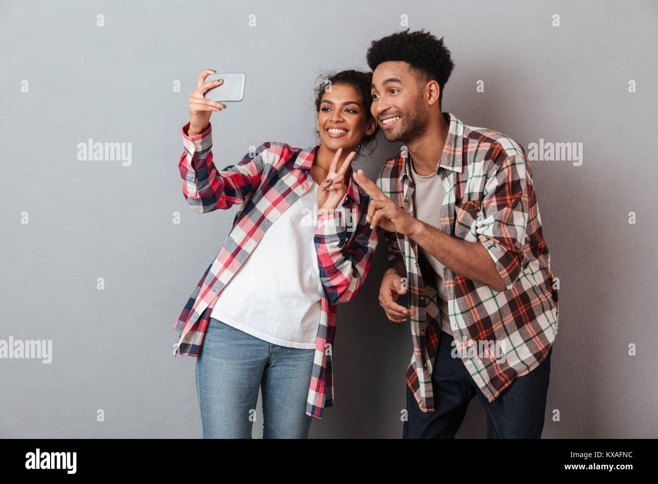 Portrait of a happy young african couple showing peace gesture while ...