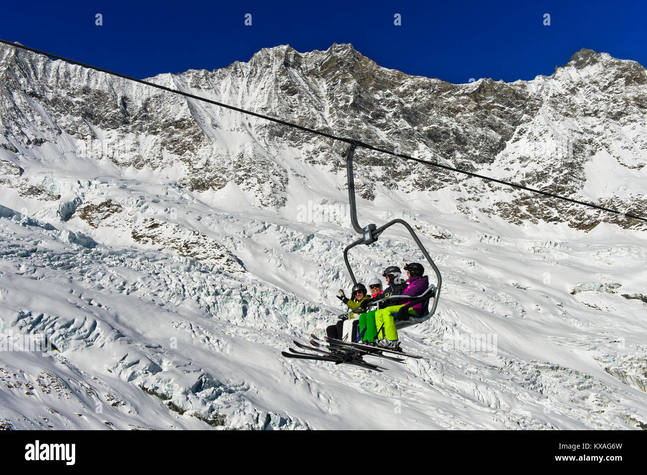 Skiers on a chairlift in front of the Feegletscher and the peaks Dom and Lenzspitze,Mischabel Group,Saas-Fee ski area,Valais Stock Photo