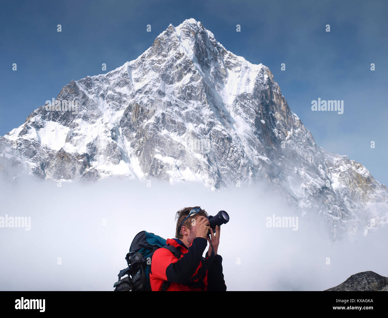 Trekker is taking picture while mount Cholatse is rising above clouds, Khumbu, Nepal Stock Photo