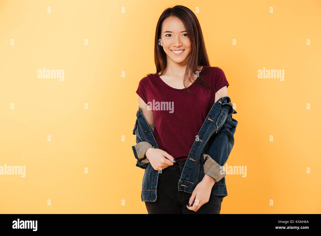 Pleased asian woman in denim jacket posing and looking at the camera ...