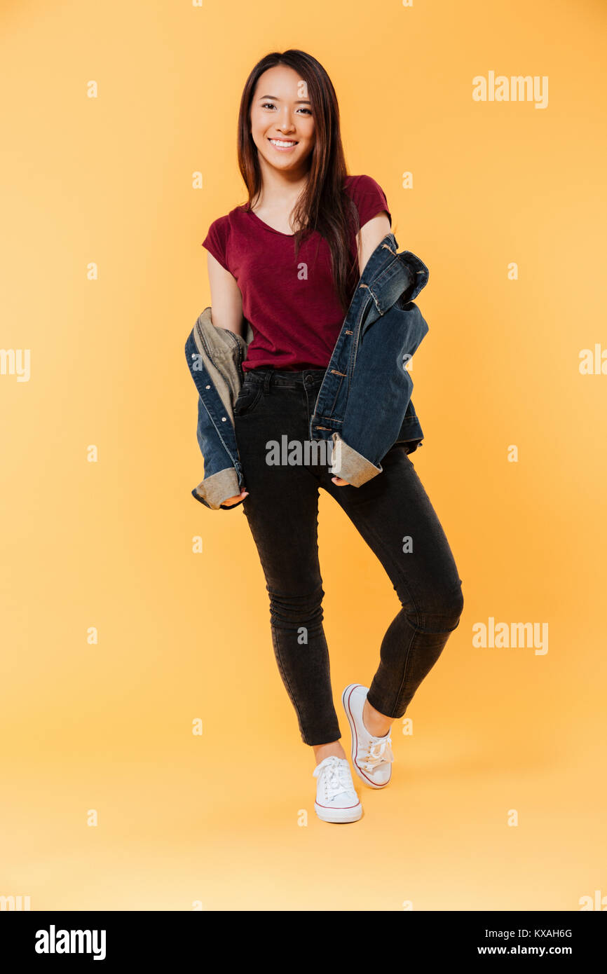 Full length image of Happy asian woman in denim jacket posing and ...