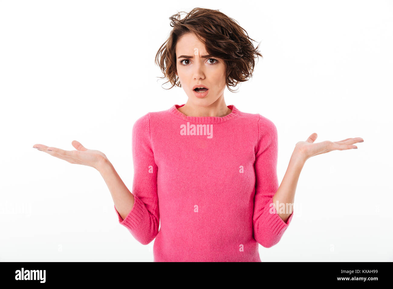 Portrait of a confused young girl shrugging shoulders and looking at camera isolated over white background Stock Photo