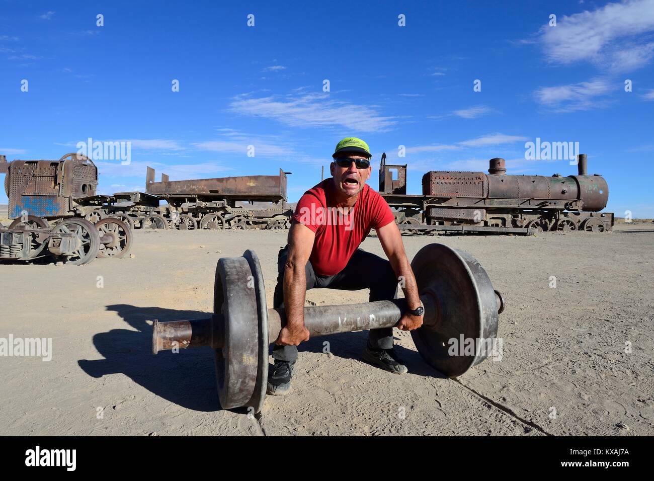 Tourist uses axle as barbell, railway cemetery, Uyuni, Potosi, Bolivia