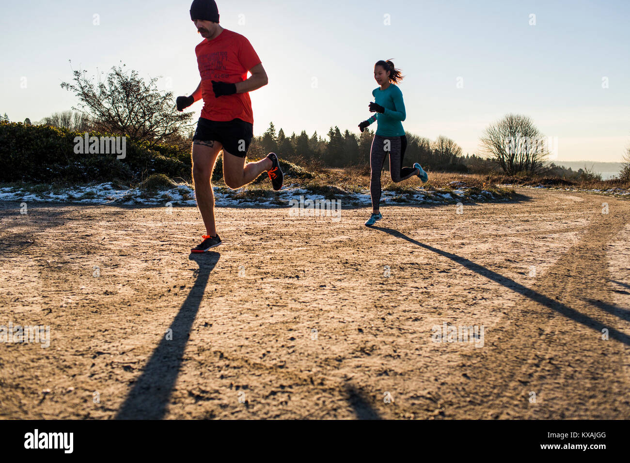 Man and woman jogging on dirt road in winter, Discovery Park, Seattle, Washington State, USA Stock Photo