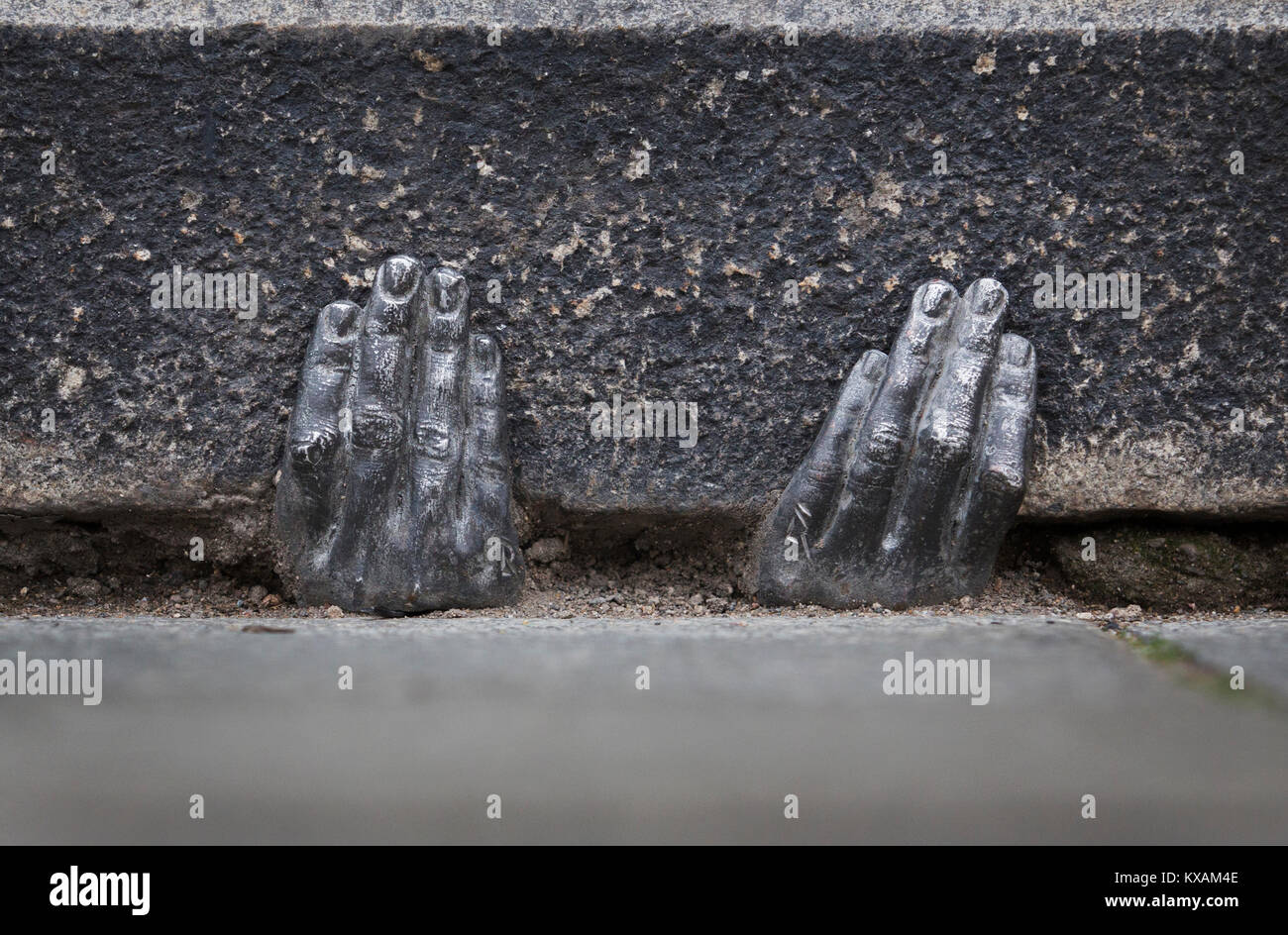 Two mysterious metal hands come out of a crack of a curb of the cathedral of St. Bartholomew in Pilsen, Czech Republic, on January 8, 2018. Officially, nobody knows who gave it into a crack about the end of the last year, or whether it have any meaning. (CTK Photo/Miroslav Chaloupka) Stock Photo