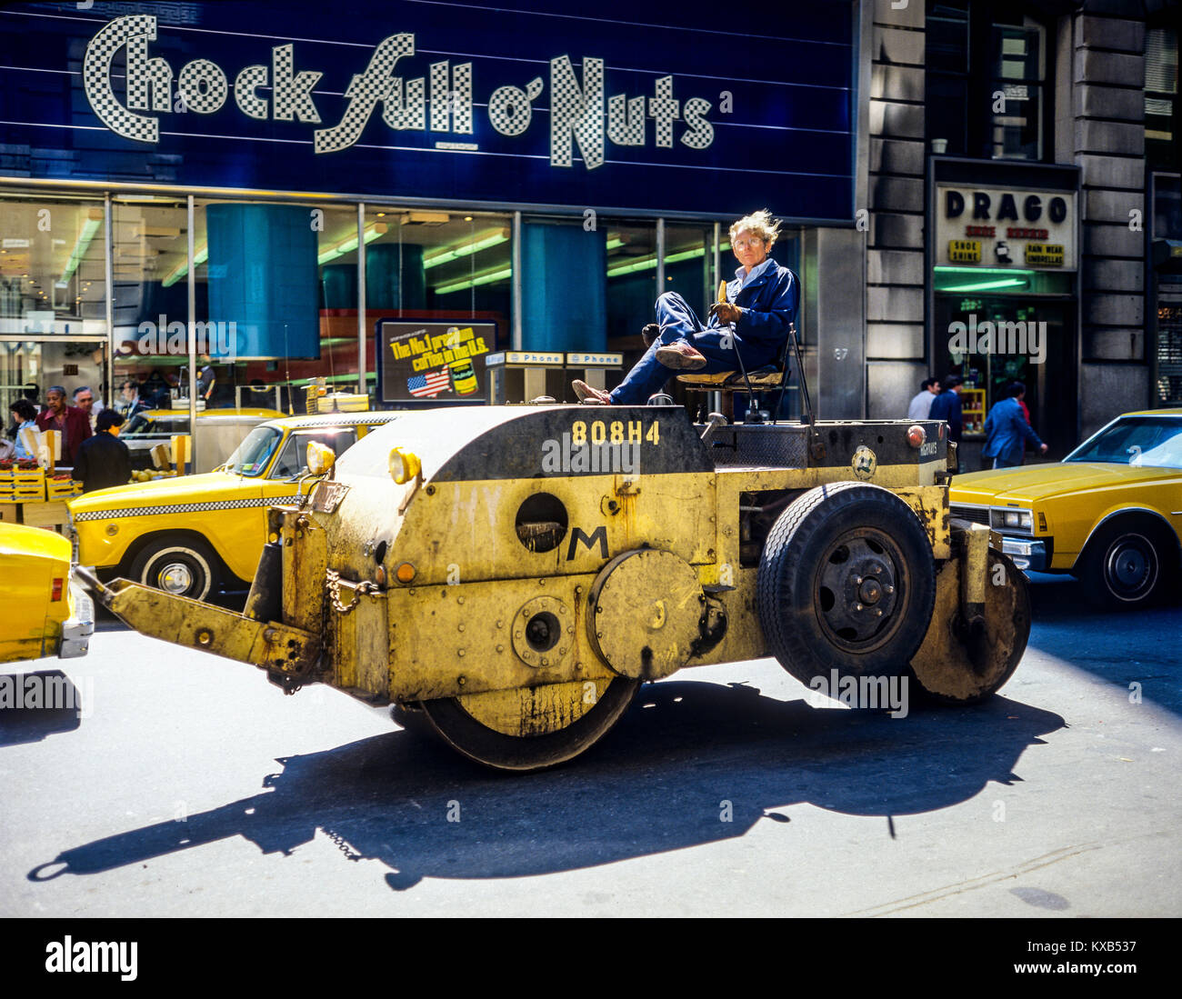 New York 1980s, man driving a yellow roadroller, Chock full of o'Nuts store, West 34th street, Manhattan, New York City, NYC, NY, USA, Stock Photo
