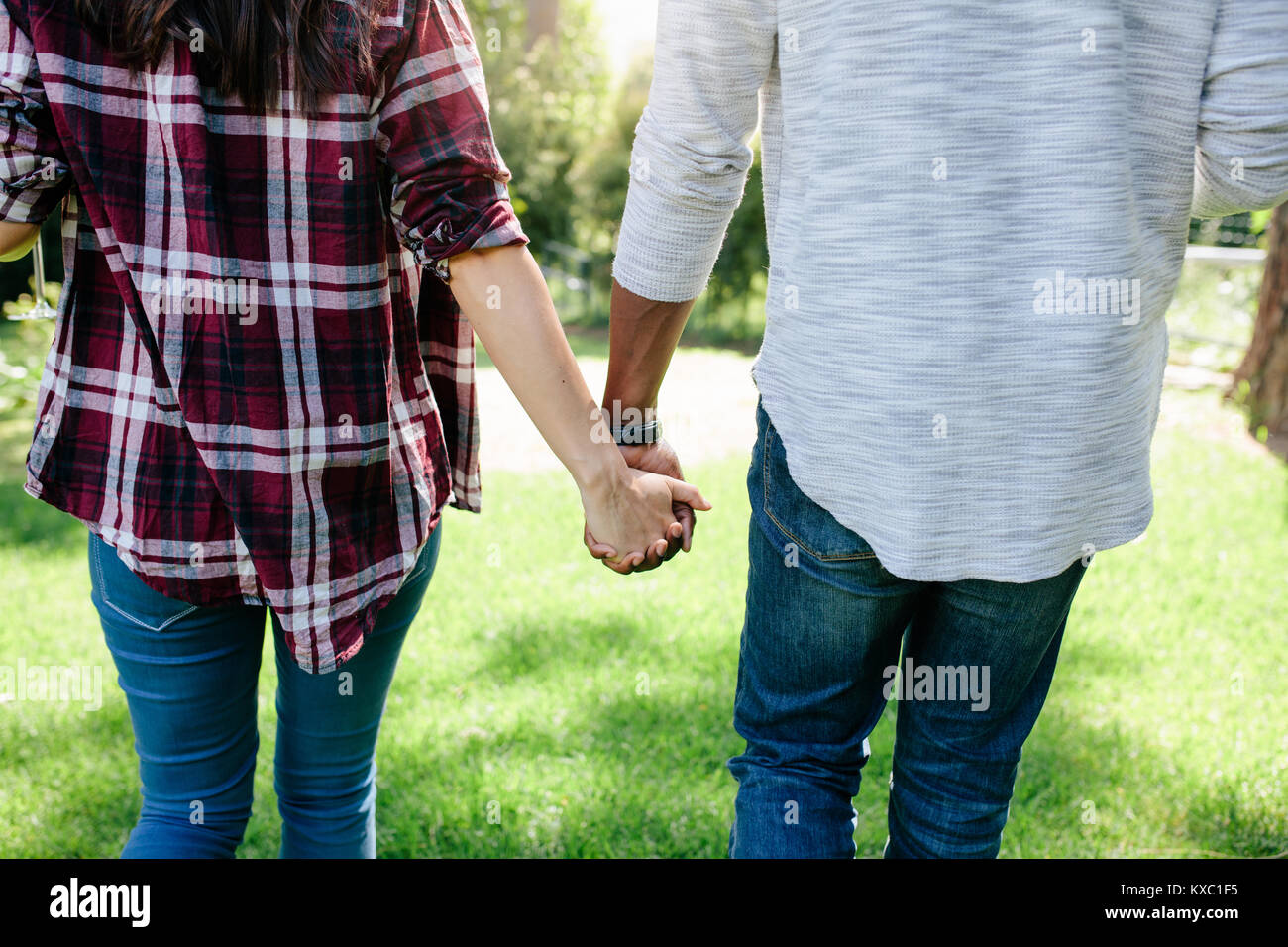Rear view of loving couple holding hands outdoors, on date in park