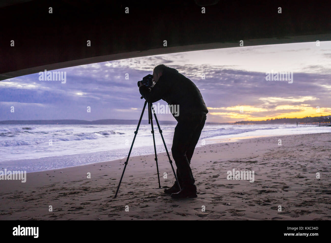 Silhouette of a male photographer taking photographs with a tripod during sunset, Bournemouth, England, UK Stock Photo